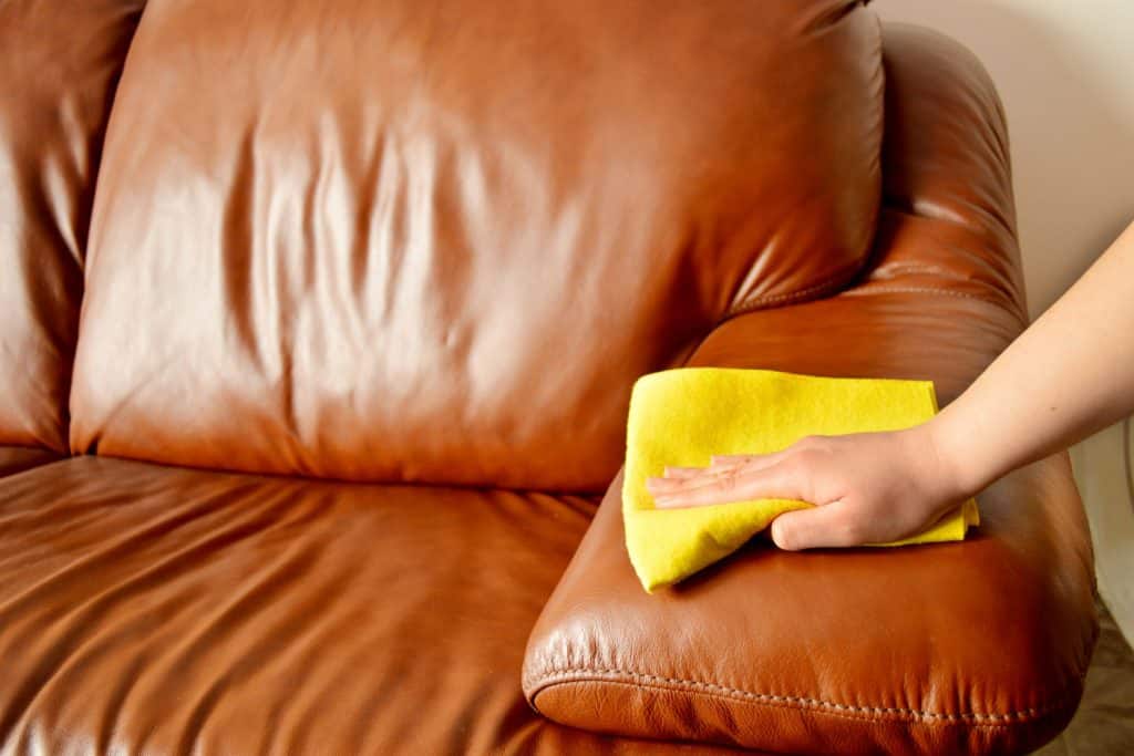 A woman cleaning a brown leather sofa