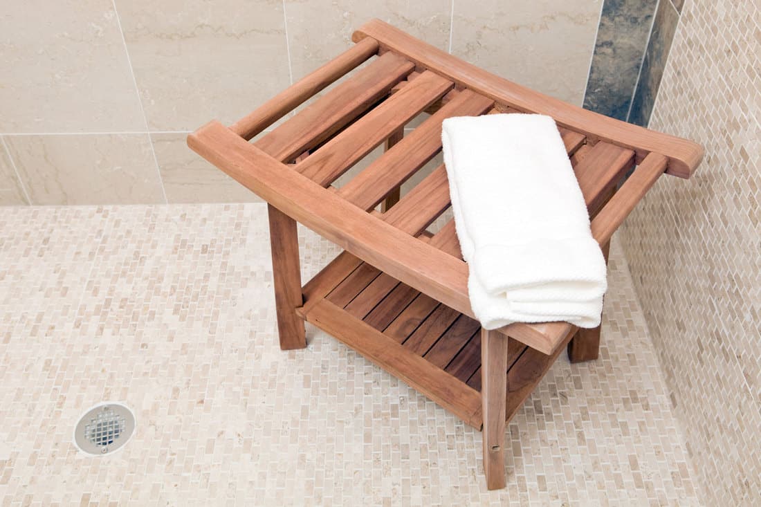 A wooden shower bench inside a modern bathroom