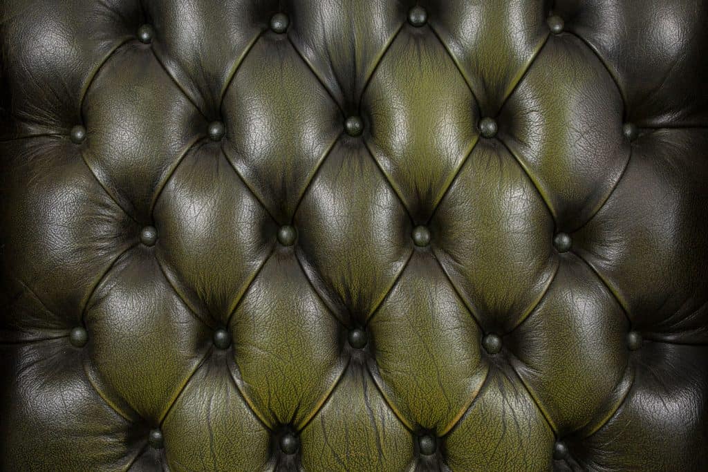 An upclose photo of an olive green colored Natuzzi leather sofa 