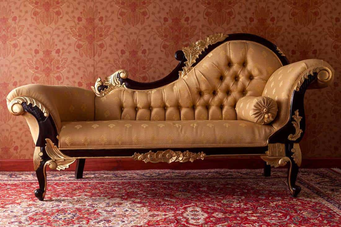 Antique black and gold ornate chaise lounge in living room with carpet floor, How Long And How Wide Is A Chaise Lounge