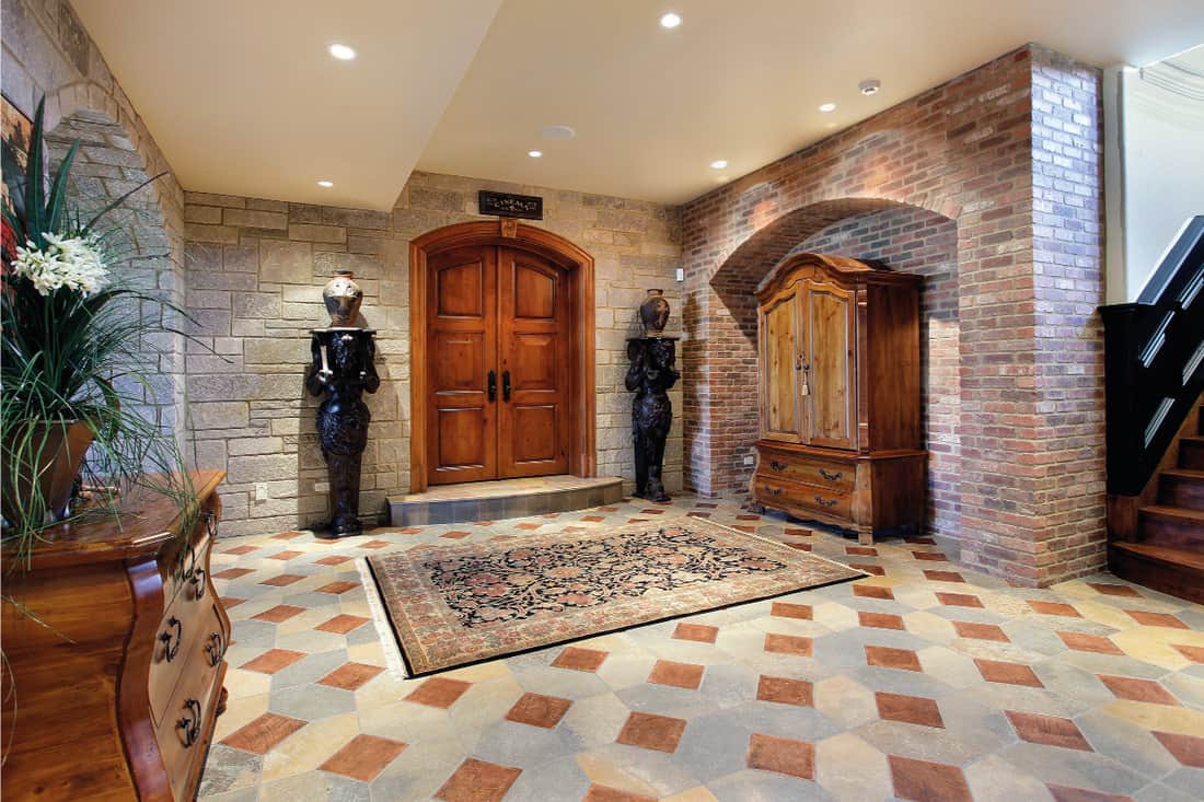 Basement foyer area vintage style with statues on the sides of a wooden door, How Big Should A Foyer Rug Be?