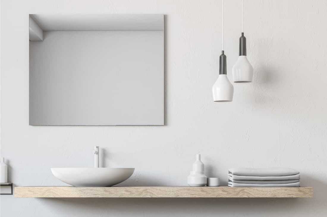 Bathroom sink and square mirror hung on a drywall