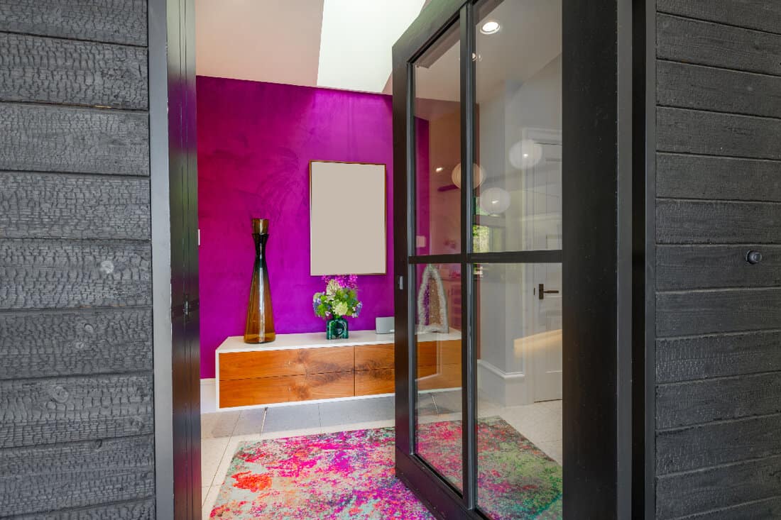 Colorful entry way with purple wall vase of flowers black glass door and mosaic rug