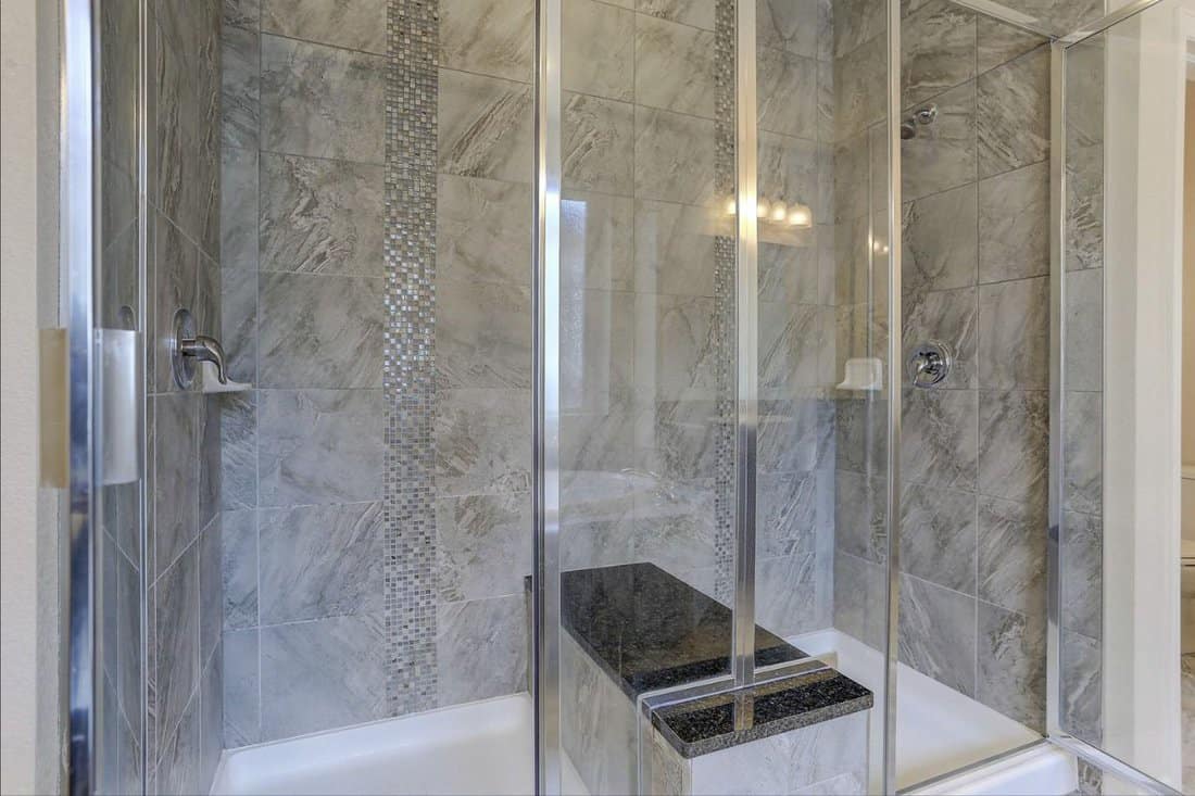 Contemporary double-shower with marble tiles and bench seat