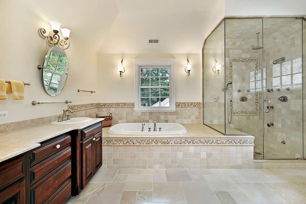 Salle de bains luxueuse peinte en crème avec une immense baignoire équipée, un meuble-lavabo en bois dur et une douche murale en verre