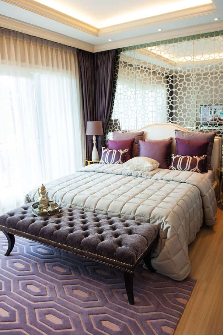 Elegant bedroom suite with purple color, purple carpet, pillows and curtains