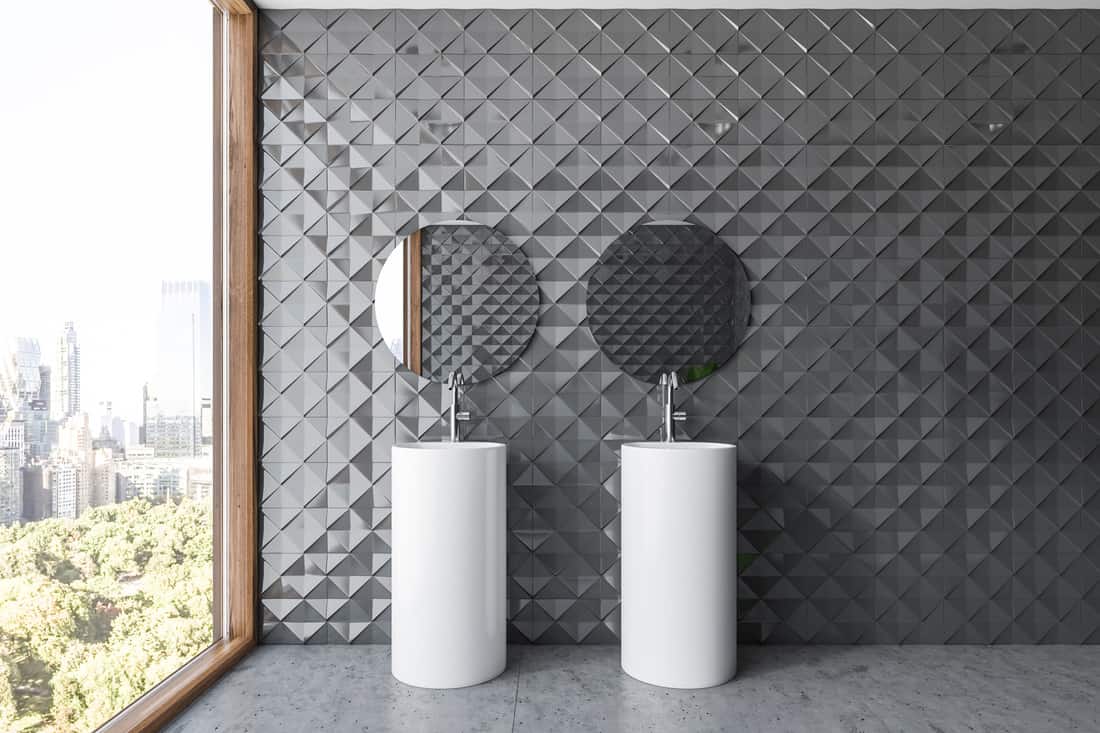 Gray tile bathroom interior, double sink, double hanging frameless mirror