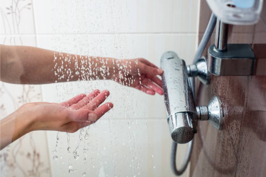Mains d'une jeune femme prenant une douche chaude à la maison