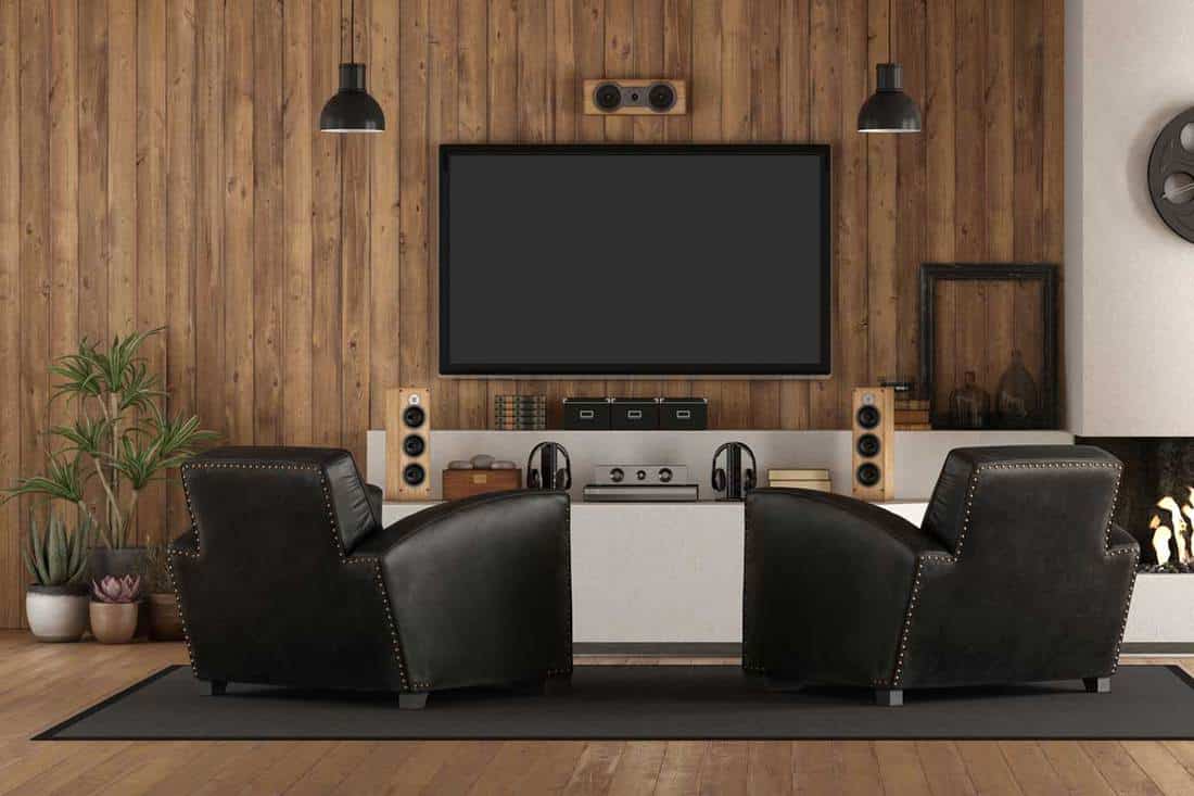 Home cinema in rustic style with black armchair, fireplace and wooden paneling, What Colors Go With Brown Paneling?