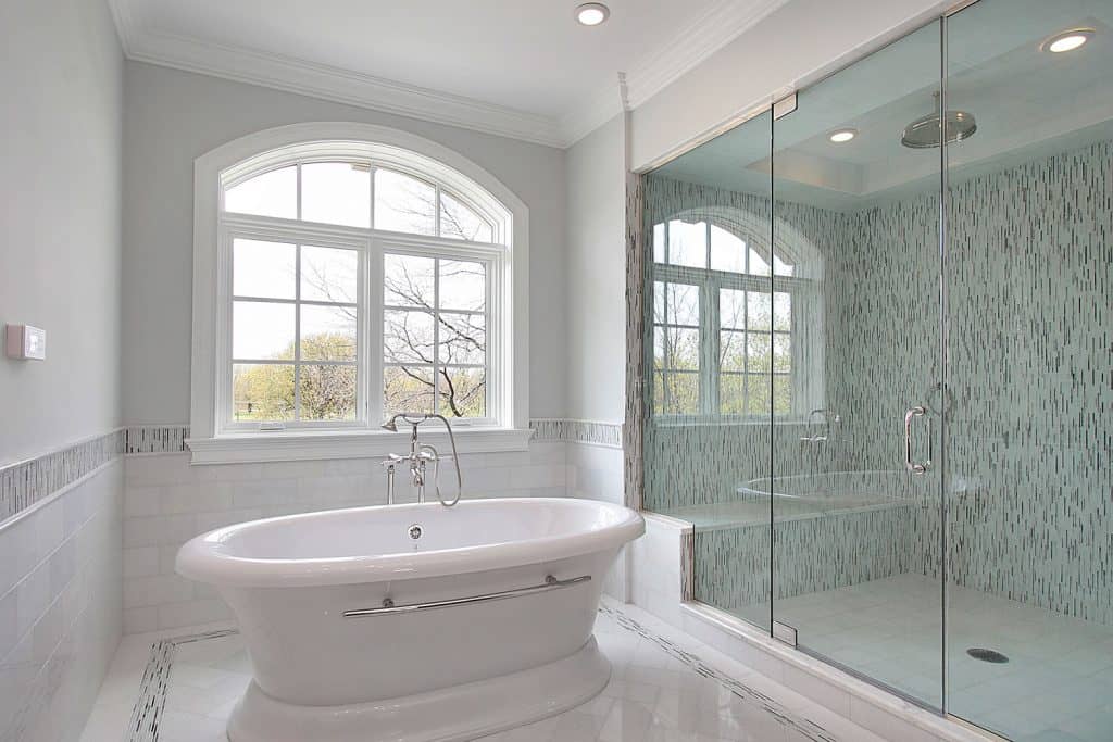 Immense salle de bain moderne blanche avec une douche murale en verre avec un banc de douche