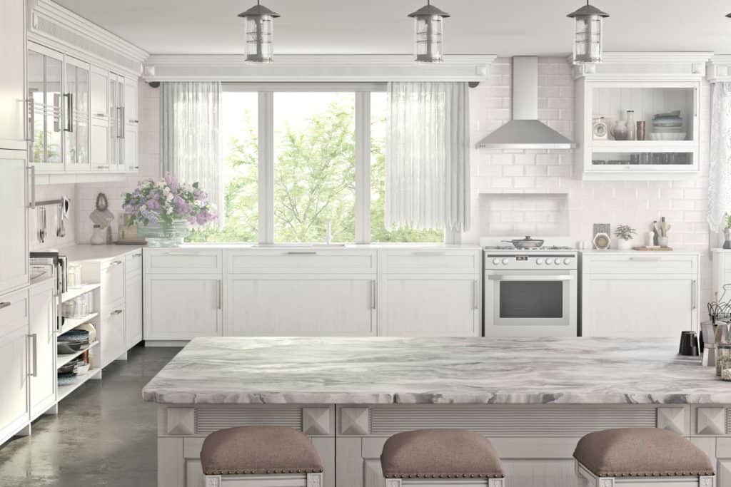 Intérieur d'une immense et spacieuse cuisine d'inspiration blanche avec un comptoir en marbre et des armoires à panneaux blancs