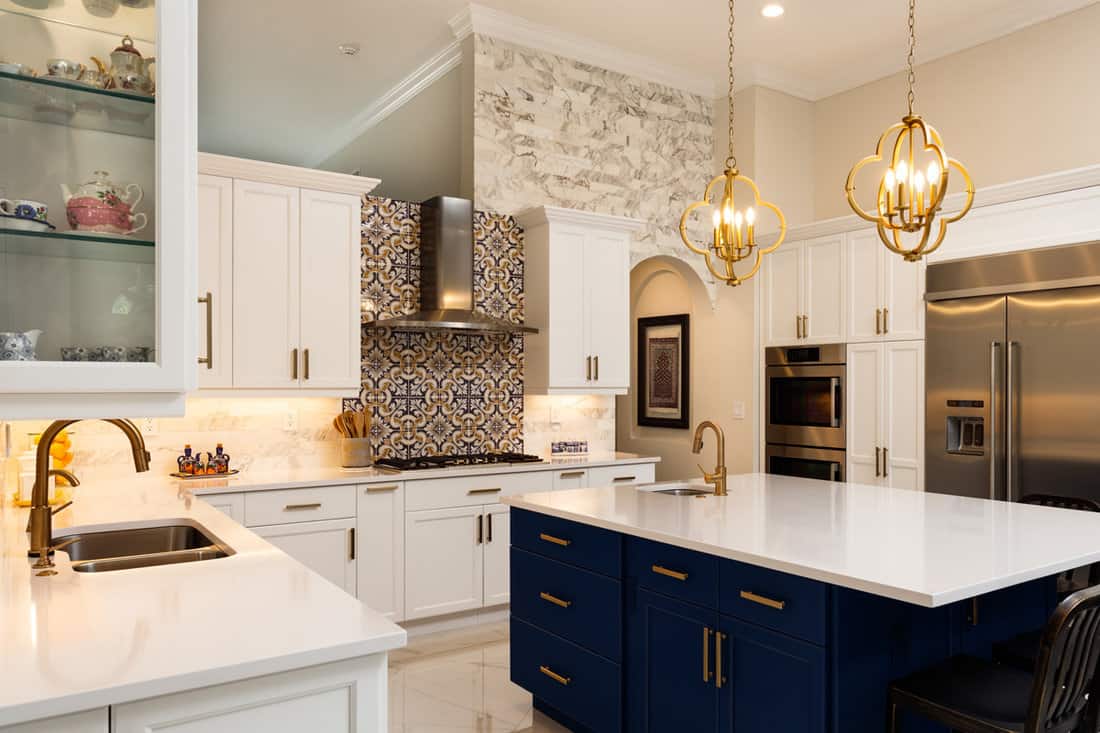 Interior of an extremely luxurious kitchen with quarts countertop and white cabinets matched with blue cabinets