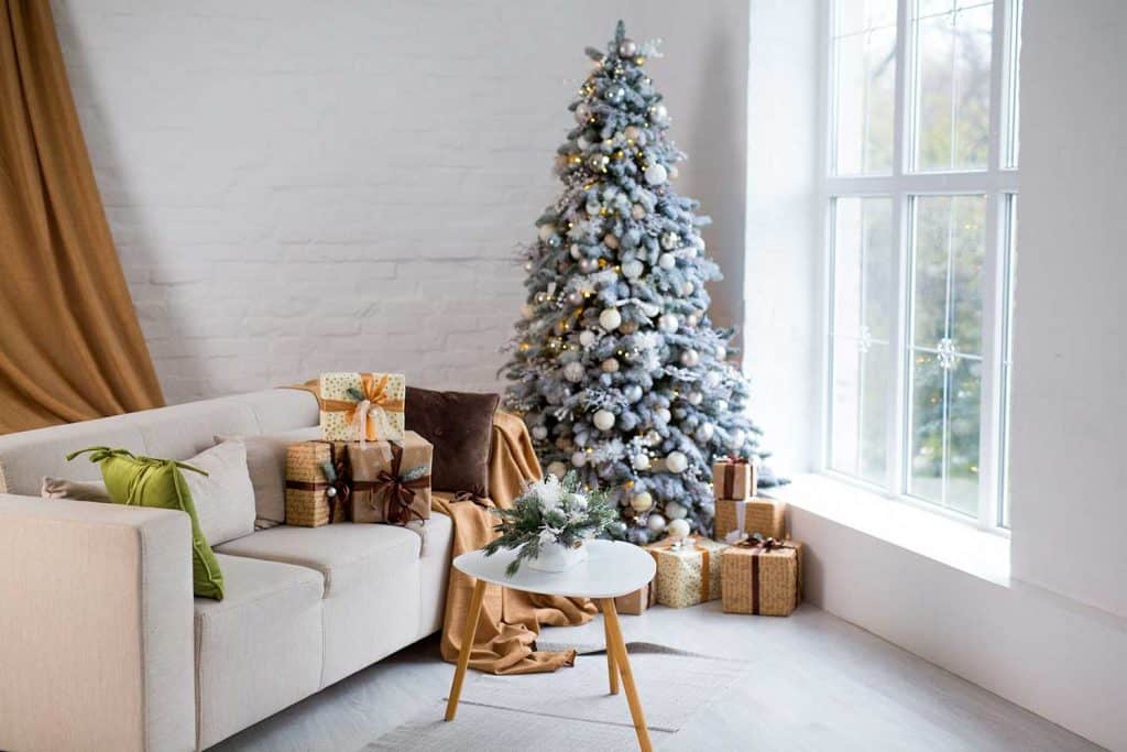 Interior of bright modern living room with comfortable sofa decorated with Christmas tree and gifts