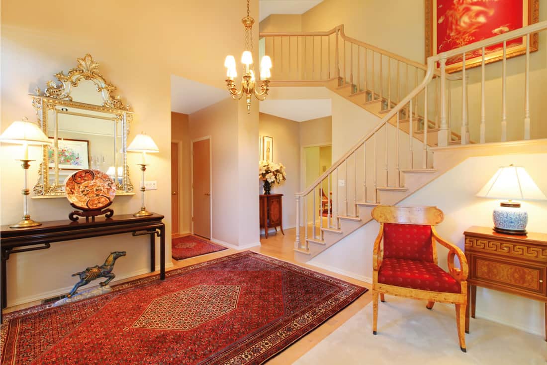 Luxury entrance living room with red rug, staircase, well spaced foyer rug