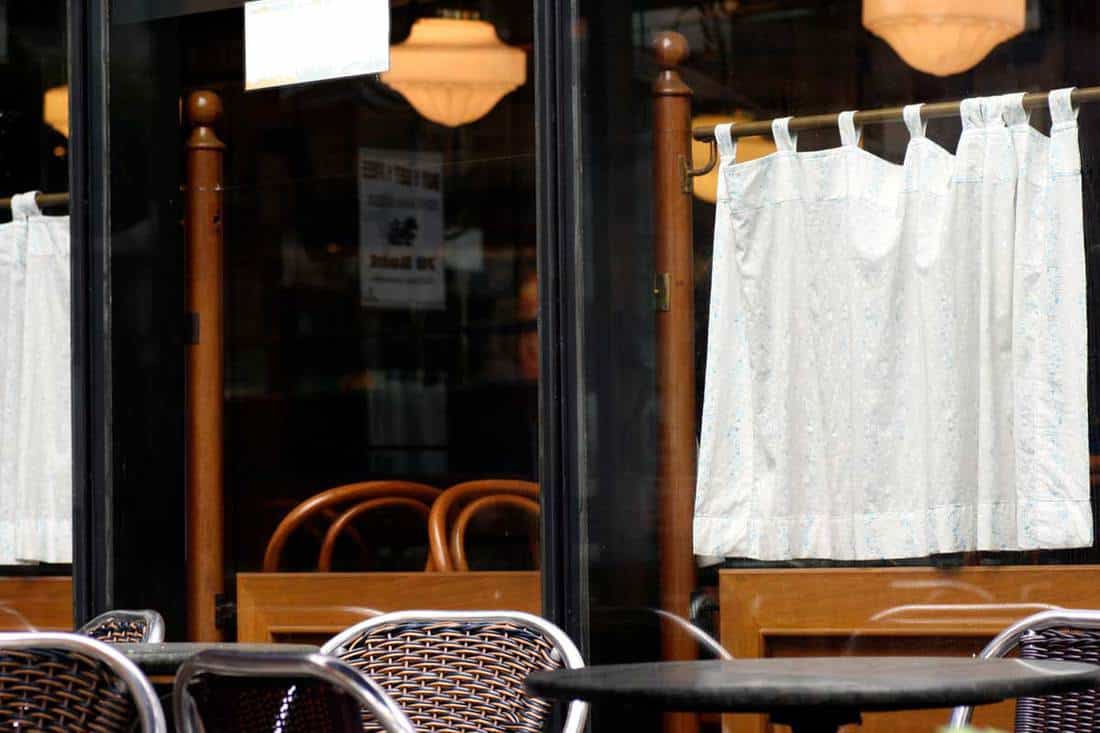 Outside of a cafe with white curtains on glass windows, tables and chairs, How To Measure For Cafe Curtains