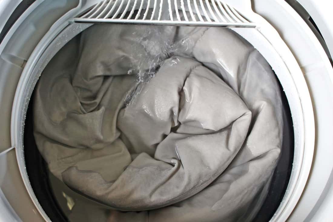 Roll up the duvet put in a washing machine. 