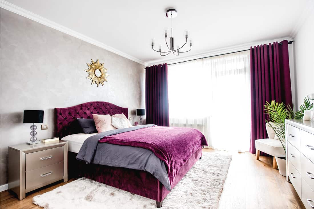 Simple and stylish bedroom interior with double bed, purple bedding and modern nightstands