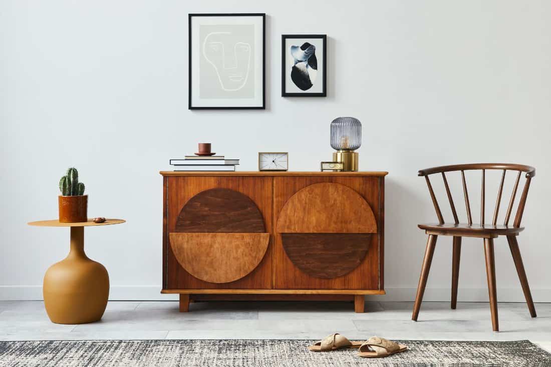 Stylish retro scandinavian living room interior with wooden commode, mock up poster frames, chiar, design stool.