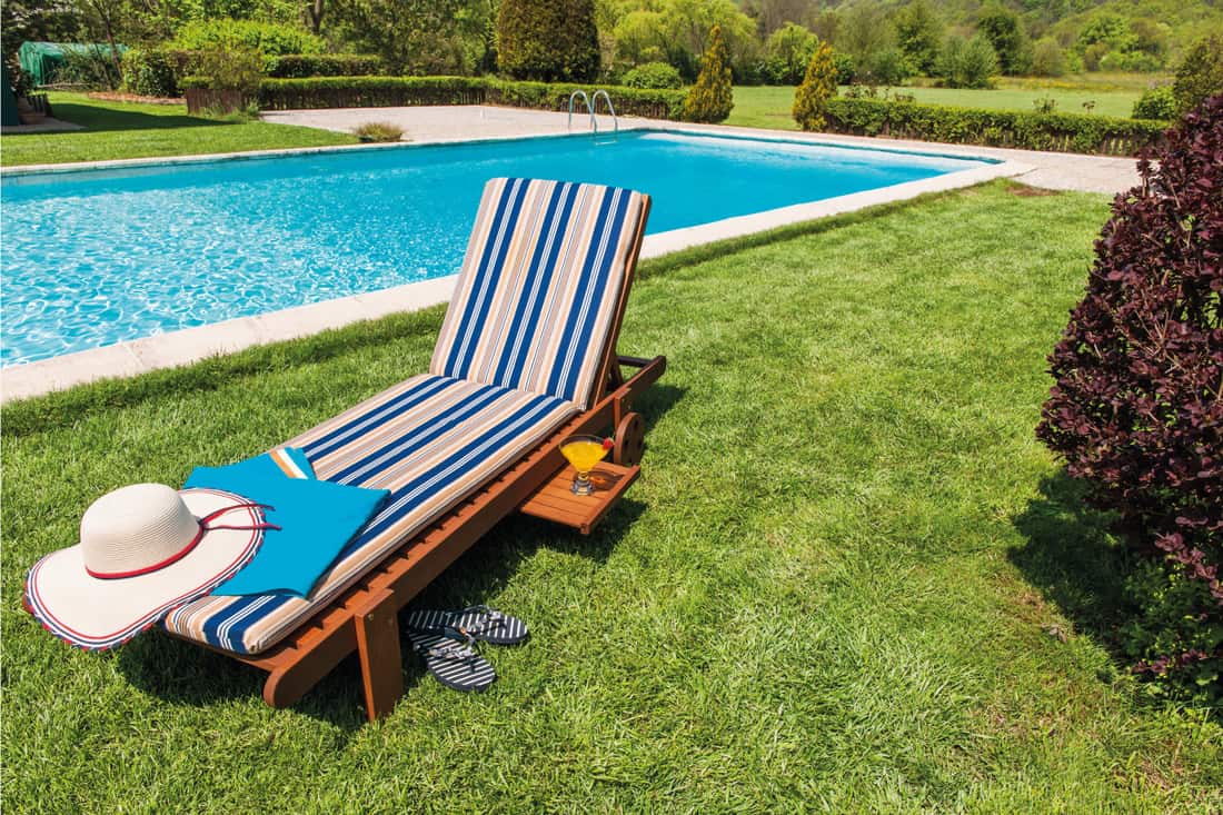 Sun-lounger, chaise lounge, straw hat and towel near the pool