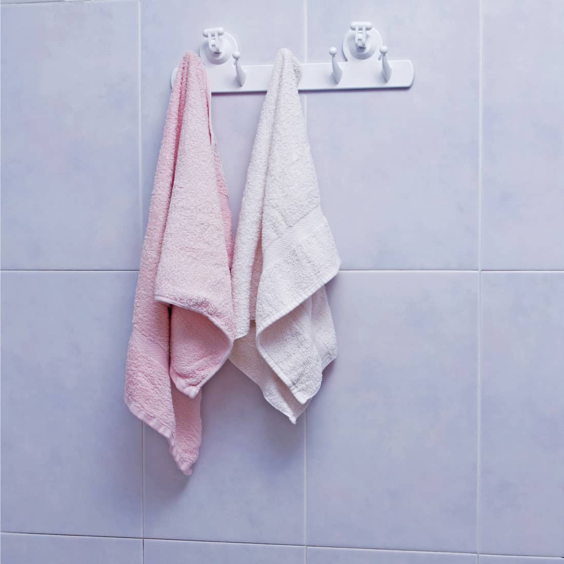 Towels hanging on the tiled wall background in the bathroom