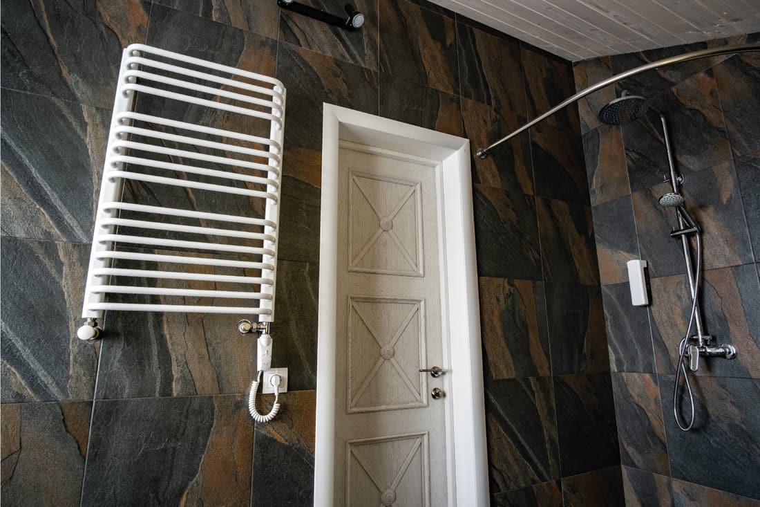 Sèche-serviettes électrique contemporain blanc monté sur un mur carrelé noir dans une salle de bains moderne