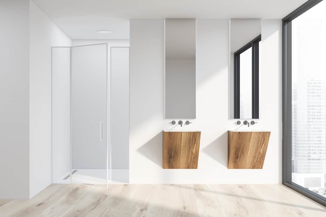 Salle de bain moderne blanche avec miroir sans cadre suspendu au-dessus des lavabos