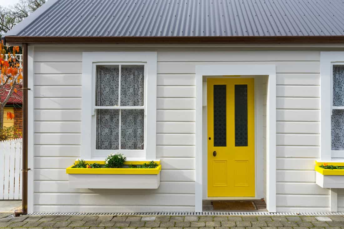 White small wooden house with yellow door 