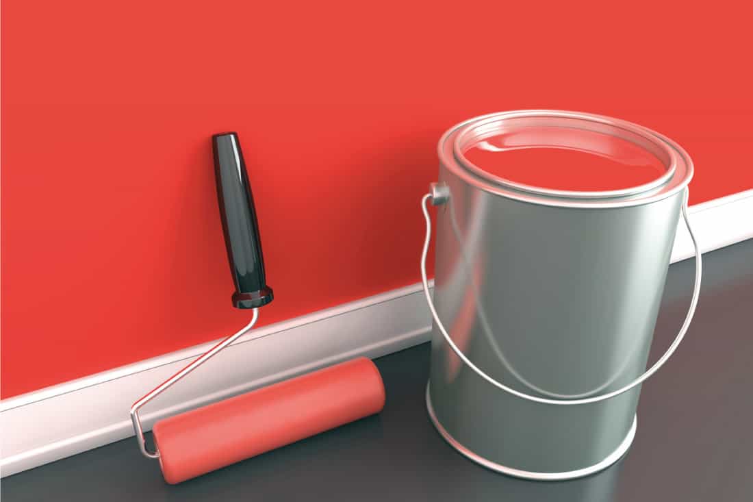 A can of red paint and a roller against a painted wood wall, How To Paint Wood Siding With A Roller [6 Steps]