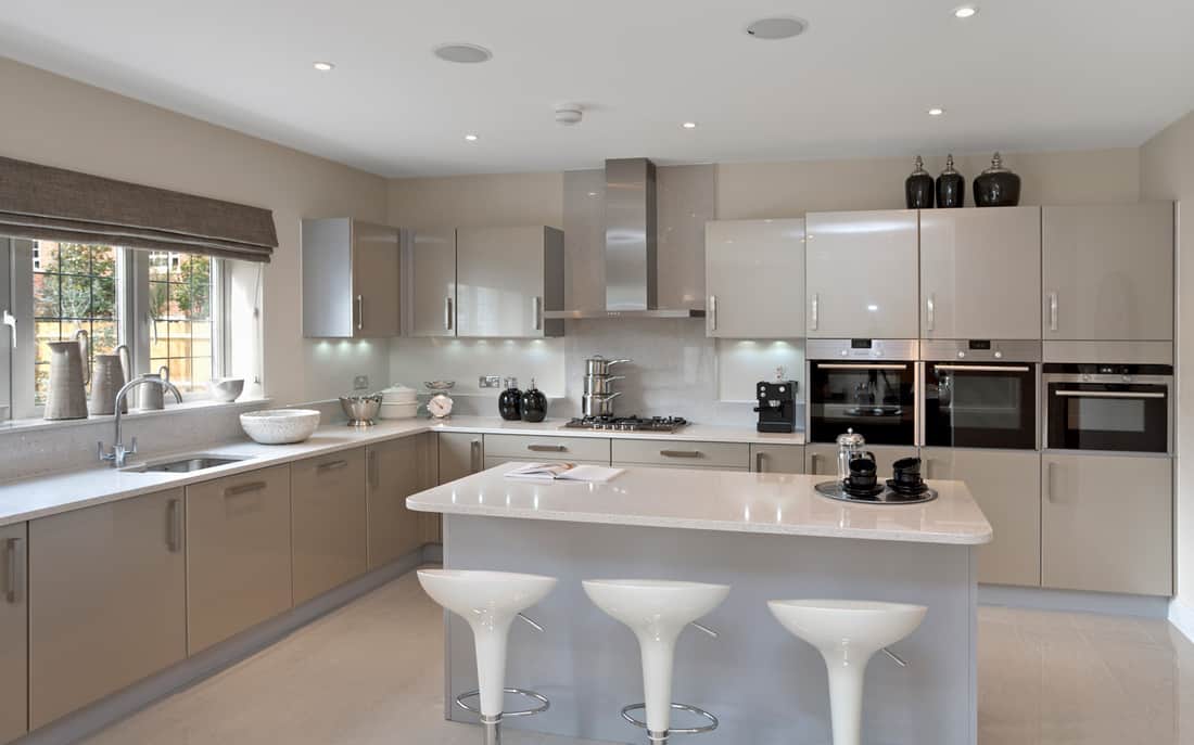 A spacious light grey kitchen from a luxury new home featuring a large island and breakfast bar