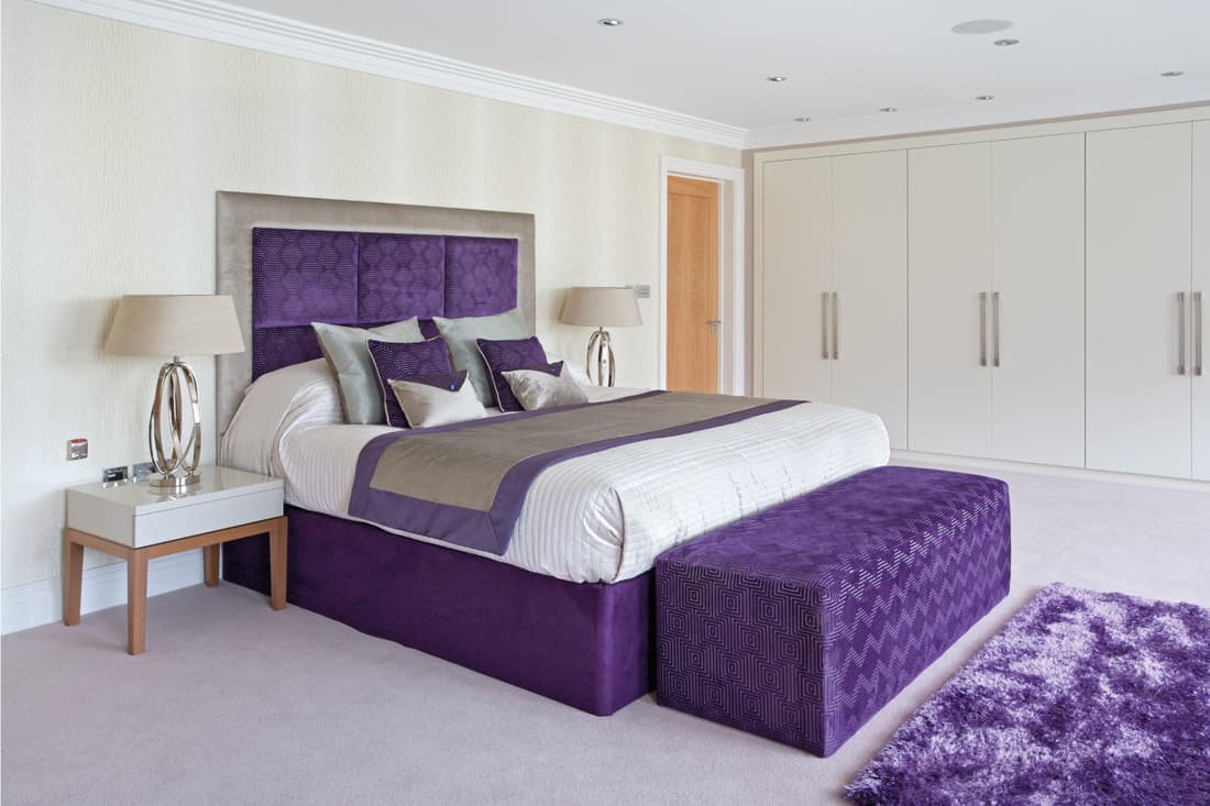 Beautifully dressed bed in purple, cream and gold in a luxury new home
