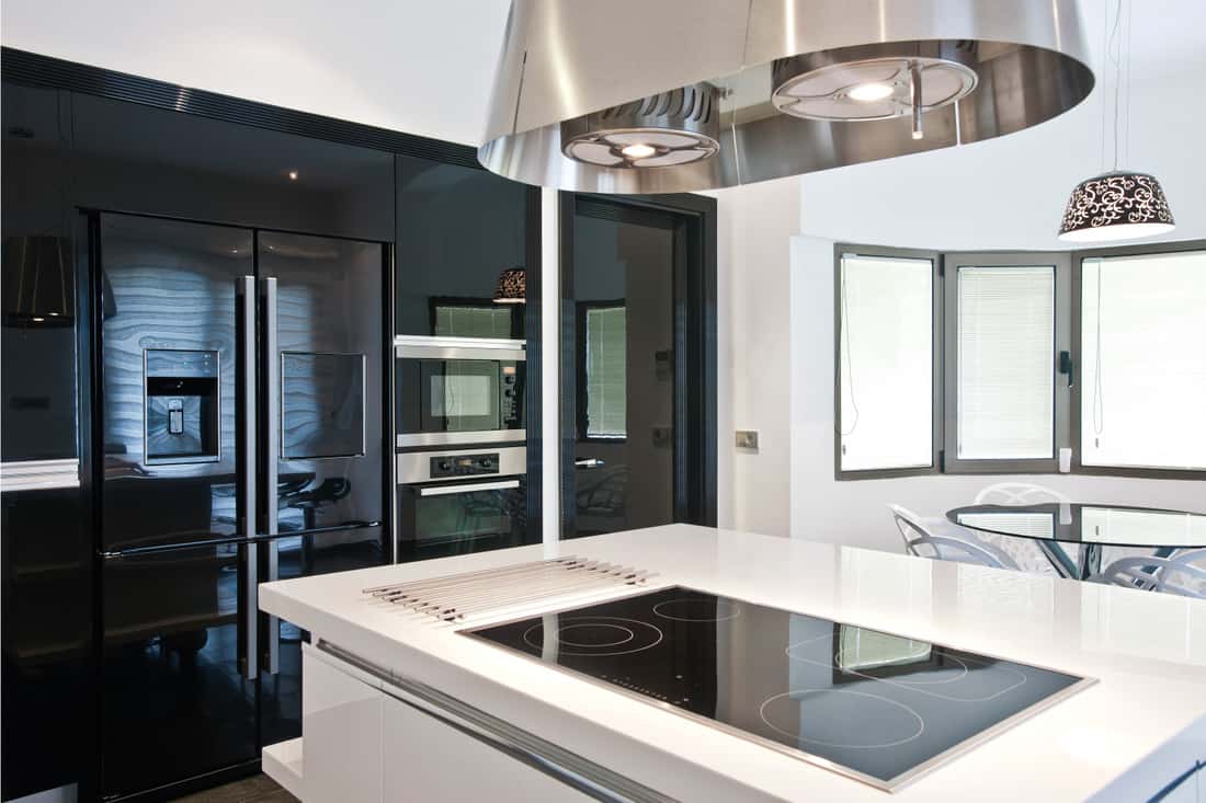 Bright modern kitchen with an island, black wall of cabinets and a stainless steel stove hood