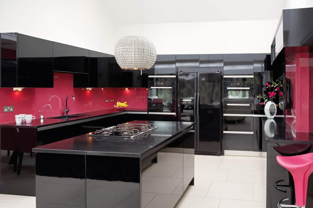 Cuisine murale rose avec armoires noires brillantes et îlot de cuisine