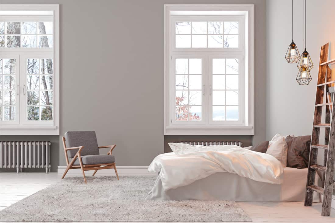 Empty bedroom interior with armchair, bed and lamp, simple and sensible gray and white bedroom