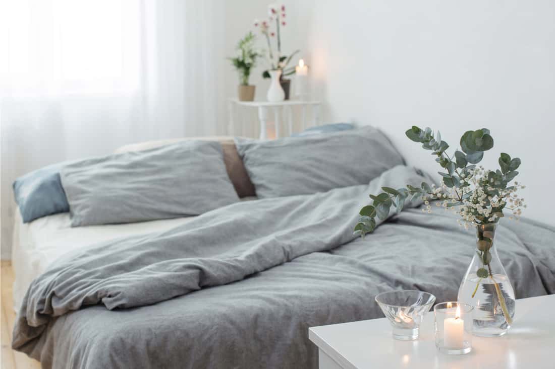 Glass votives and vases in a cool but cozy white and gray bedroom