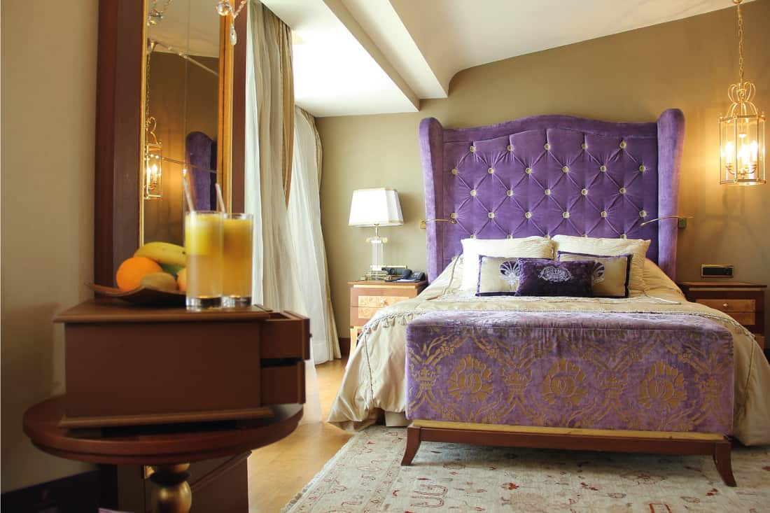 Home bedroom with curtains and bed with large purple headboard