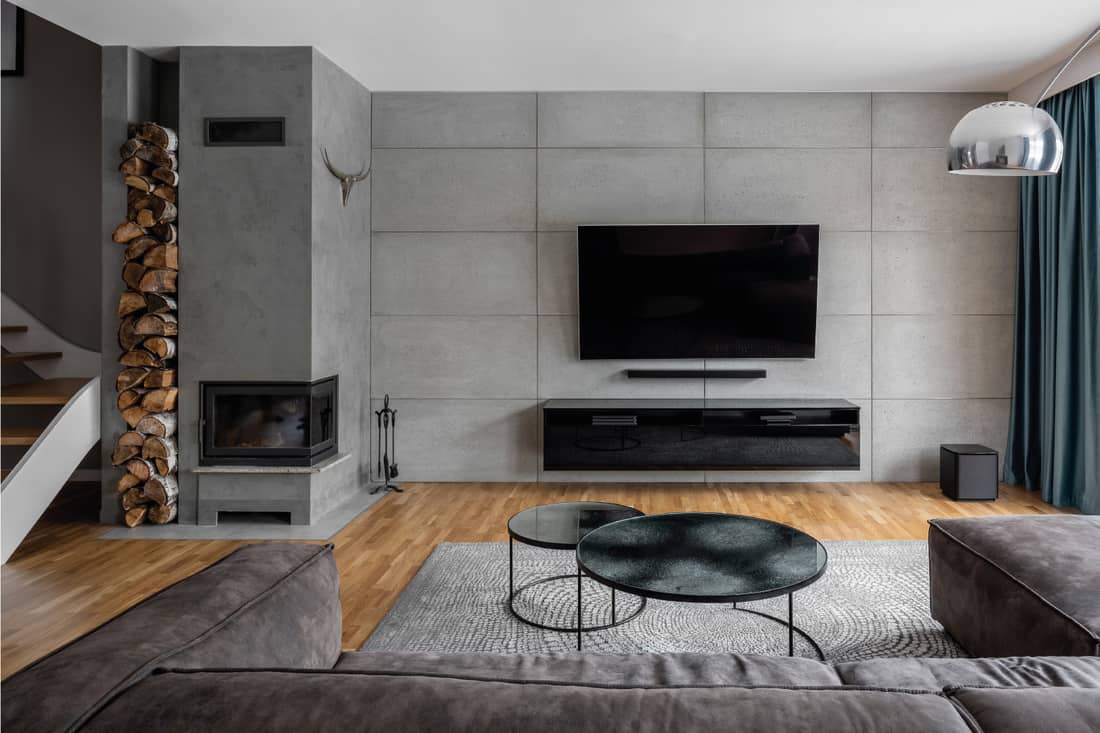 Living room with large flatscreen tv on gray cement wall and wall mounted fireplace