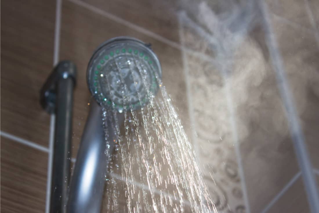 Low angle view of steaming water flowing from shower head in the bathroom, How Big Should A Steam Shower Be?
