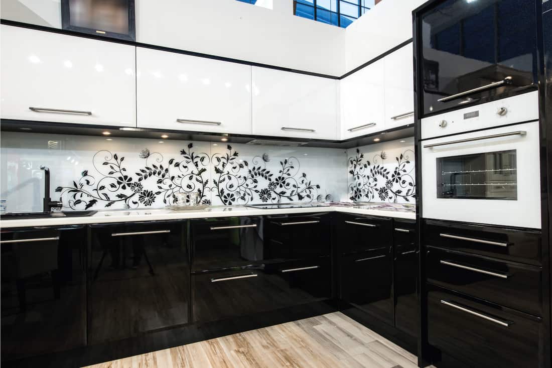 Nice kitchen interior with shiny black cabinets and printed wallpaper
