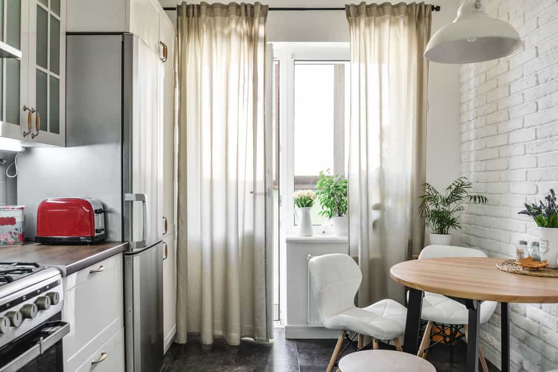 intérieur de la cuisine de style scandinave avec des meubles blancs et une table à manger dans un appartement, Comment accrocher des rideaux dans un appartement en location [4 Methods]