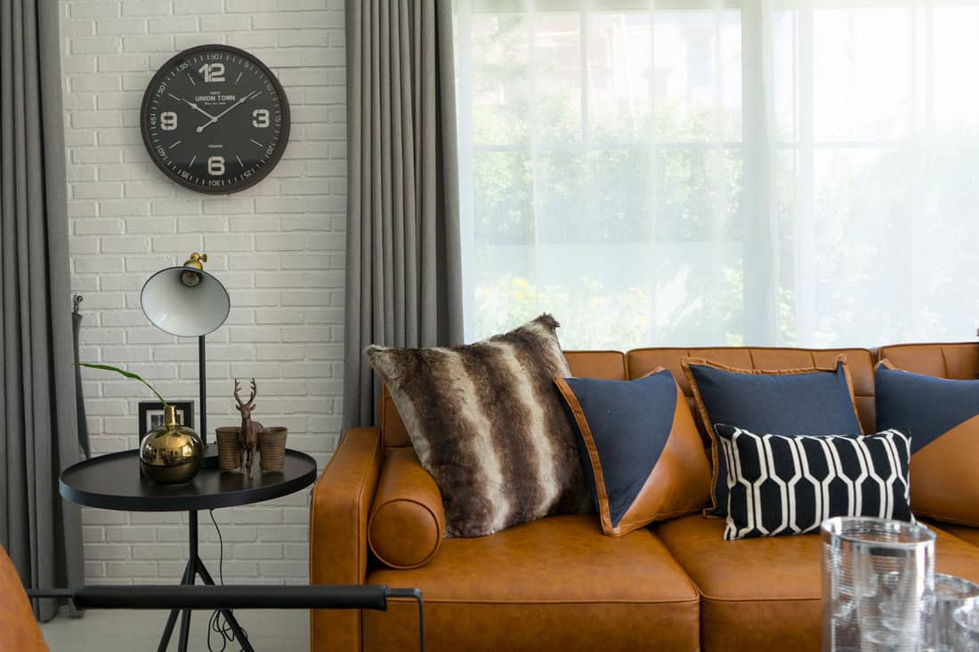 side table lamp and brown leather sofa with pattern cushions in industrial style decoration, Does Leather Furniture Stretch And Sag?