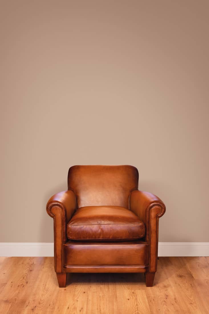Solitary traditional leather seat against a nude colored wall