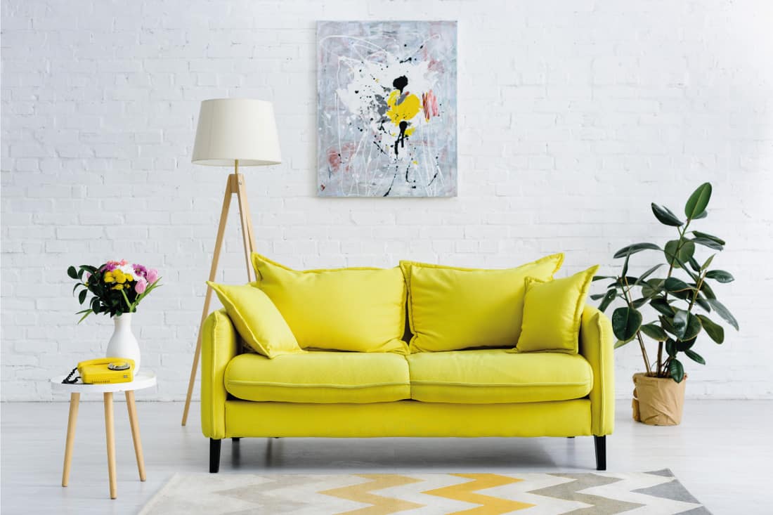 tripod floor lamp behind a yellow couch in a gray living room, 9 Best Floor Lamps For The Living Room