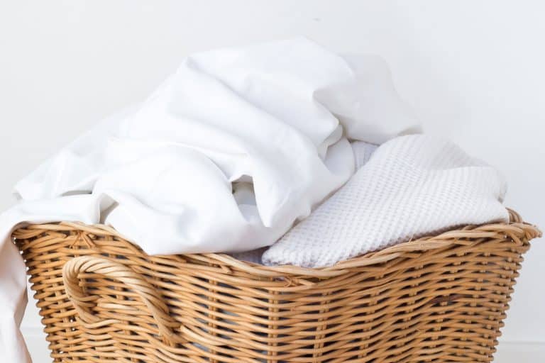 wicker laundry basket filled with dirty laundry white bedding, How To Wash White Bedding (With And Without Bleach)