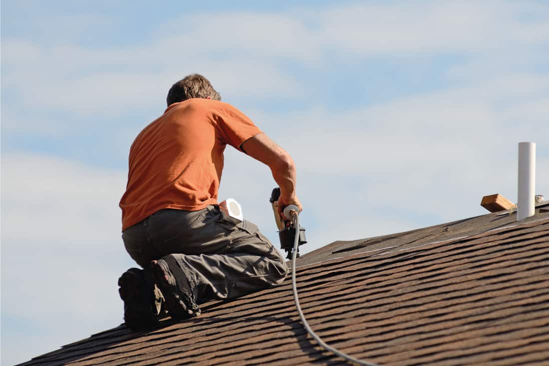 Worker installing wood roof shingles on top of a house, 6 Types Of Wood Roofs You Should Know
