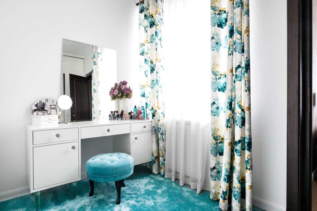 A blue themed dressing room with floral curtains, blue carpet, a small blue round chair, and a white dressing table, How Big Is A Dressing Table?