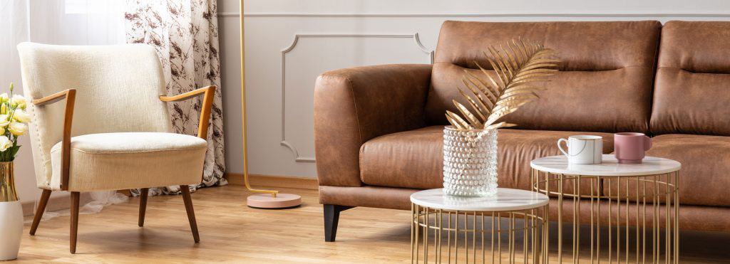 A brown leather sofa next to a white accent chair