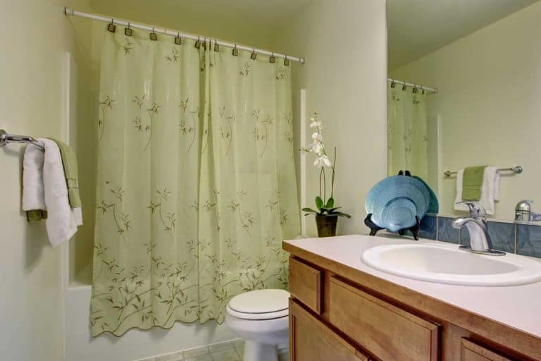 A classic bathroom with green shower curtain and tile floor, Which Side Of A Shower Curtain Liner Faces Out?