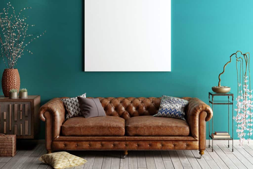 A classic brown leather sofa with a blue painted wall