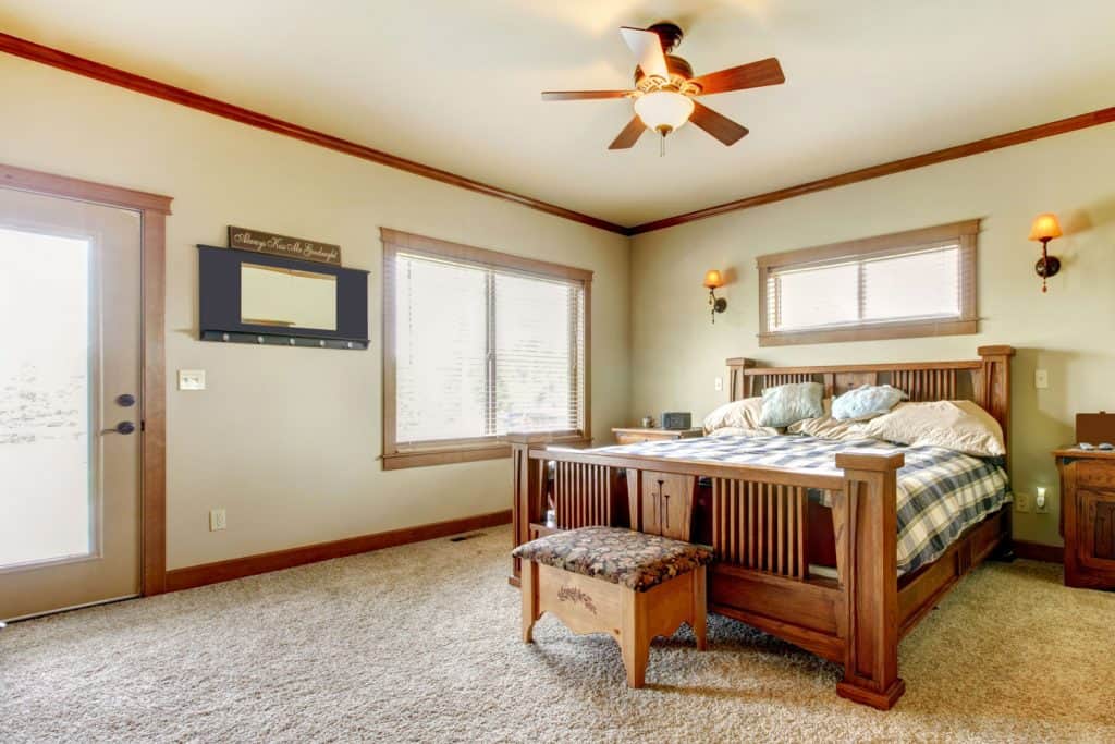 A cozy and warm rustic themed bedroom with a wooden framed bed, hardwood trims, and window casings