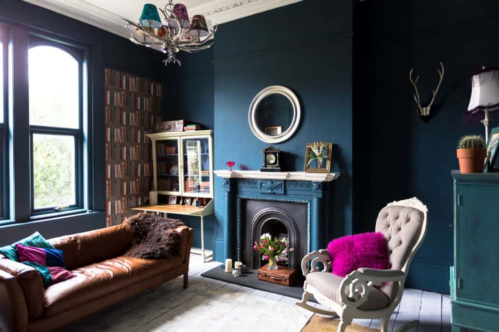 A dark blue colored living room incorporated with brown furniture's, bookshelves, and a Mediterranean inspired room architecture